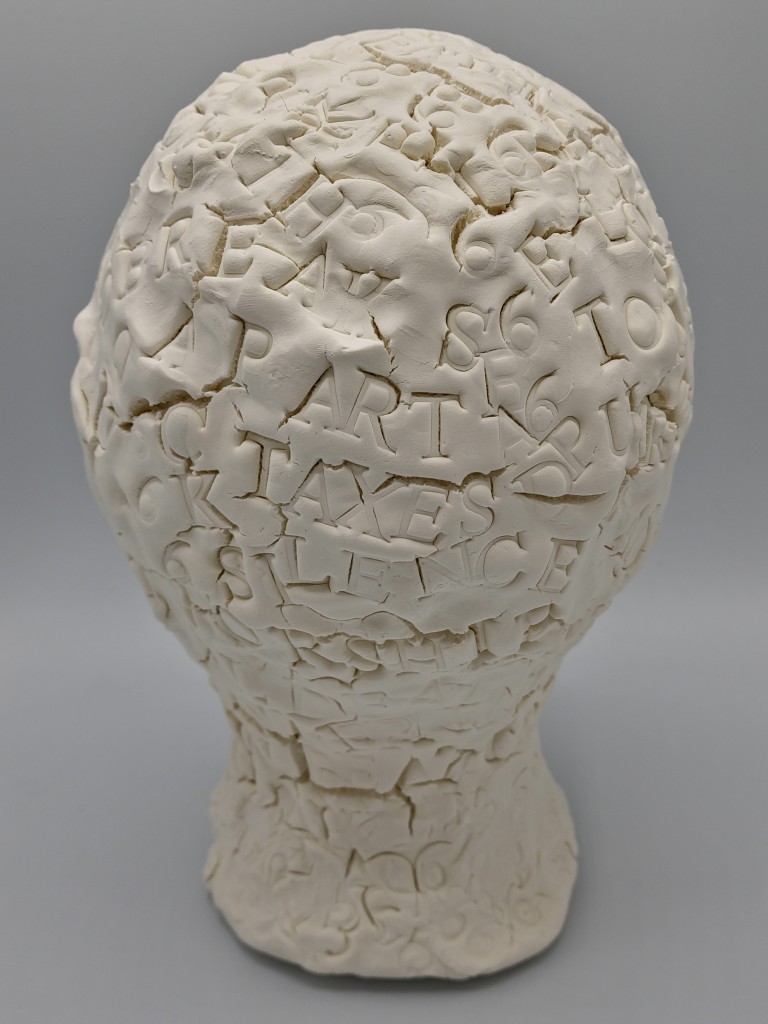 Clay Head #3 Back of the head
text includes gouged stamped words: PART TAXES ART SILENCE  scattered in wave patterns over the clay head.